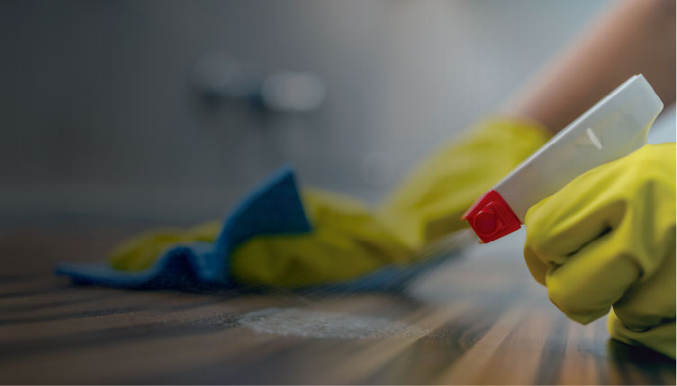 cleaning a surface with gloves and spray bottle